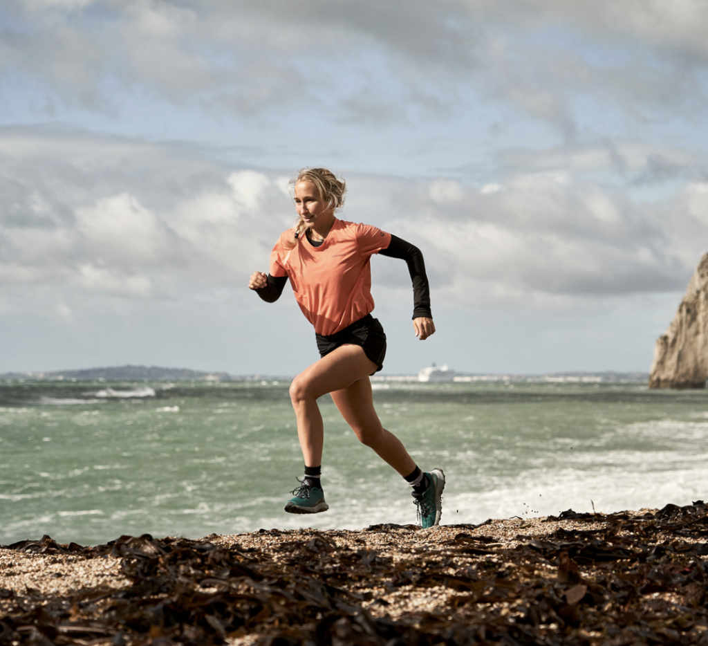 woman running in merrell trainers alongside beach