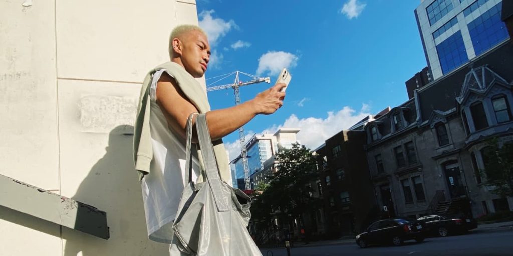 gen z man looking at phone on street