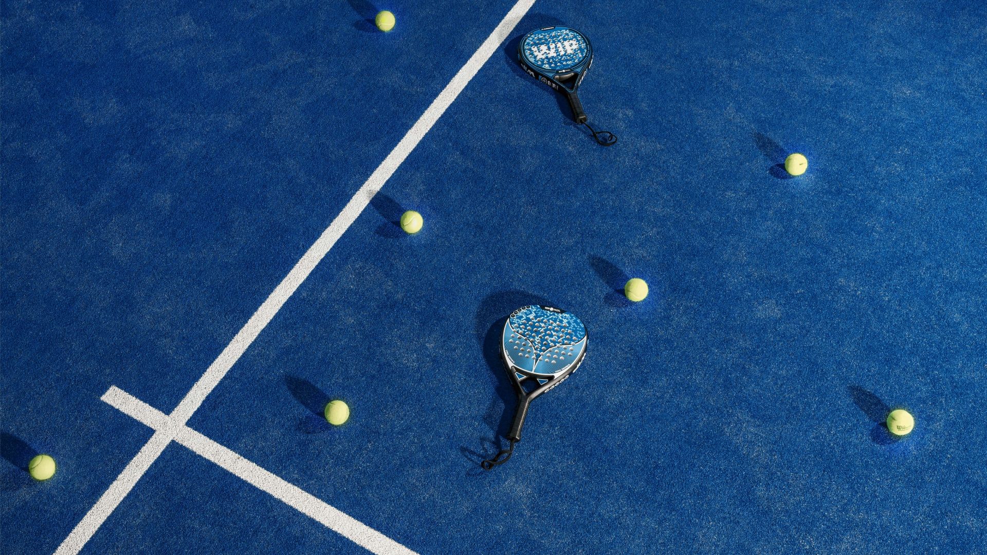 Padel paddles on a blue padel court with tennis balls