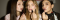 three women apply lipstick together looking into the camera